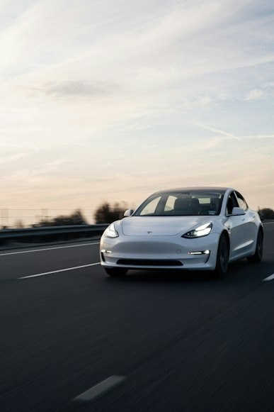 White car driving on a highway at sunset with a blurred background.